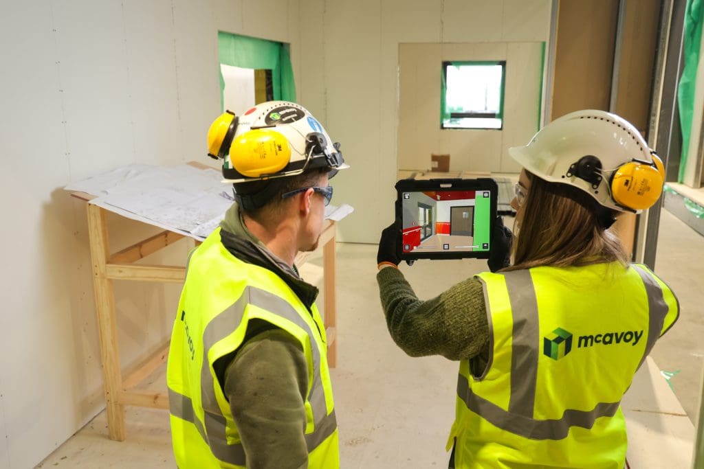 McAvoy colleagues onsite look at the layout of modules designed using DfMA princples on a tablet.