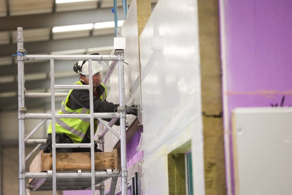 Installing cladding on a modular building for building compliance.